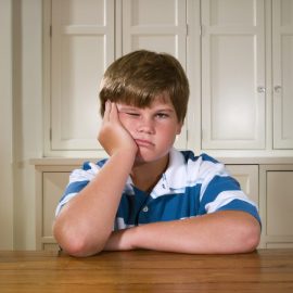 Boy (10-11) sitting behind table in house, portrait