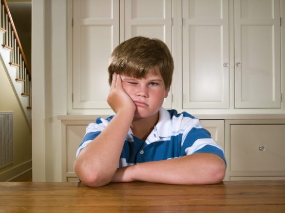 Boy (10-11) sitting behind table in house, portrait
