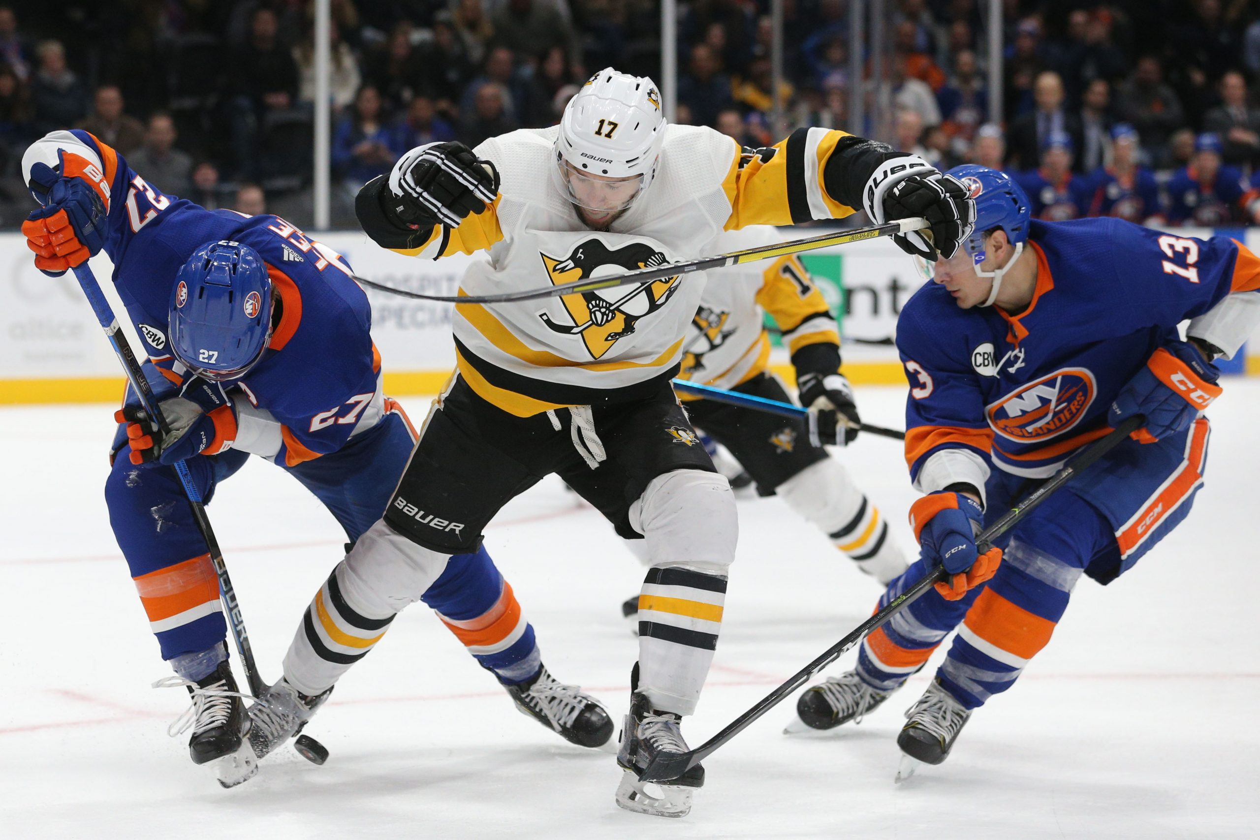 Dec 10, 2018; Uniondale, NY, USA; New York Islanders left wing Anders Lee (27) and New York Islanders center Mathew Barzal (13) fight for the puck with Pittsburgh Penguins right wing Bryan Rust (17) during overtime at Nassau Veterans Memorial Coliseum. Mandatory Credit: Brad Penner-USA TODAY Sports