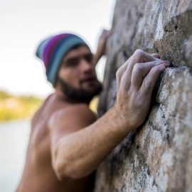 Portrait of a man climber climbing to the top of the rock.