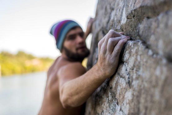 Portrait of a man climber climbing to the top of the rock.