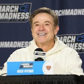 Iona Gaels head coach Rick Pitino smiles at the podium.
