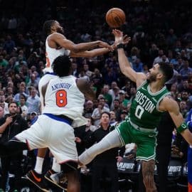Two Knicks' players stop a Celtics' player.