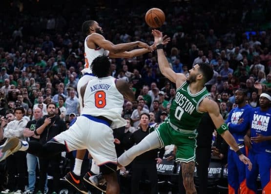 Two Knicks' players stop a Celtics' player.